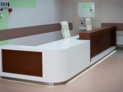 Двухуровневая стойка администратора в больнице из искусственного камня со вставками из шпона вишни