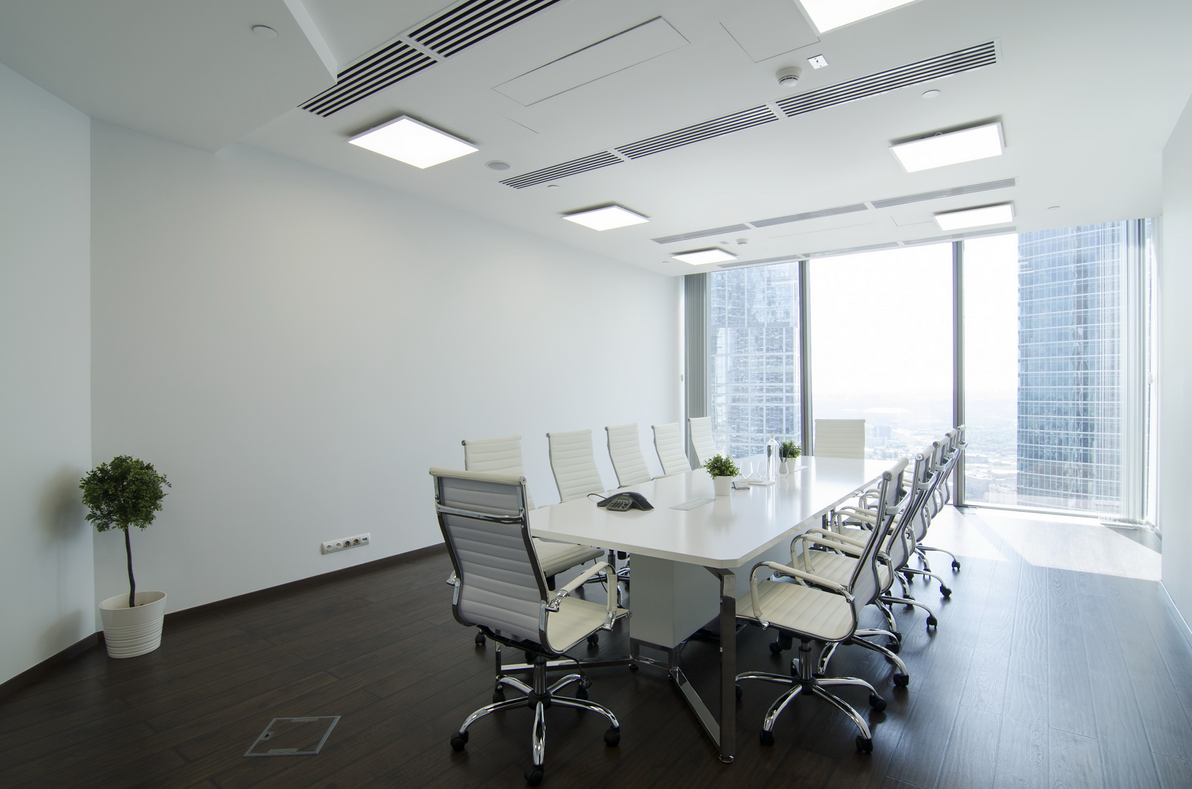 Белый стол и белые кресла для переговоров в просторном помещении